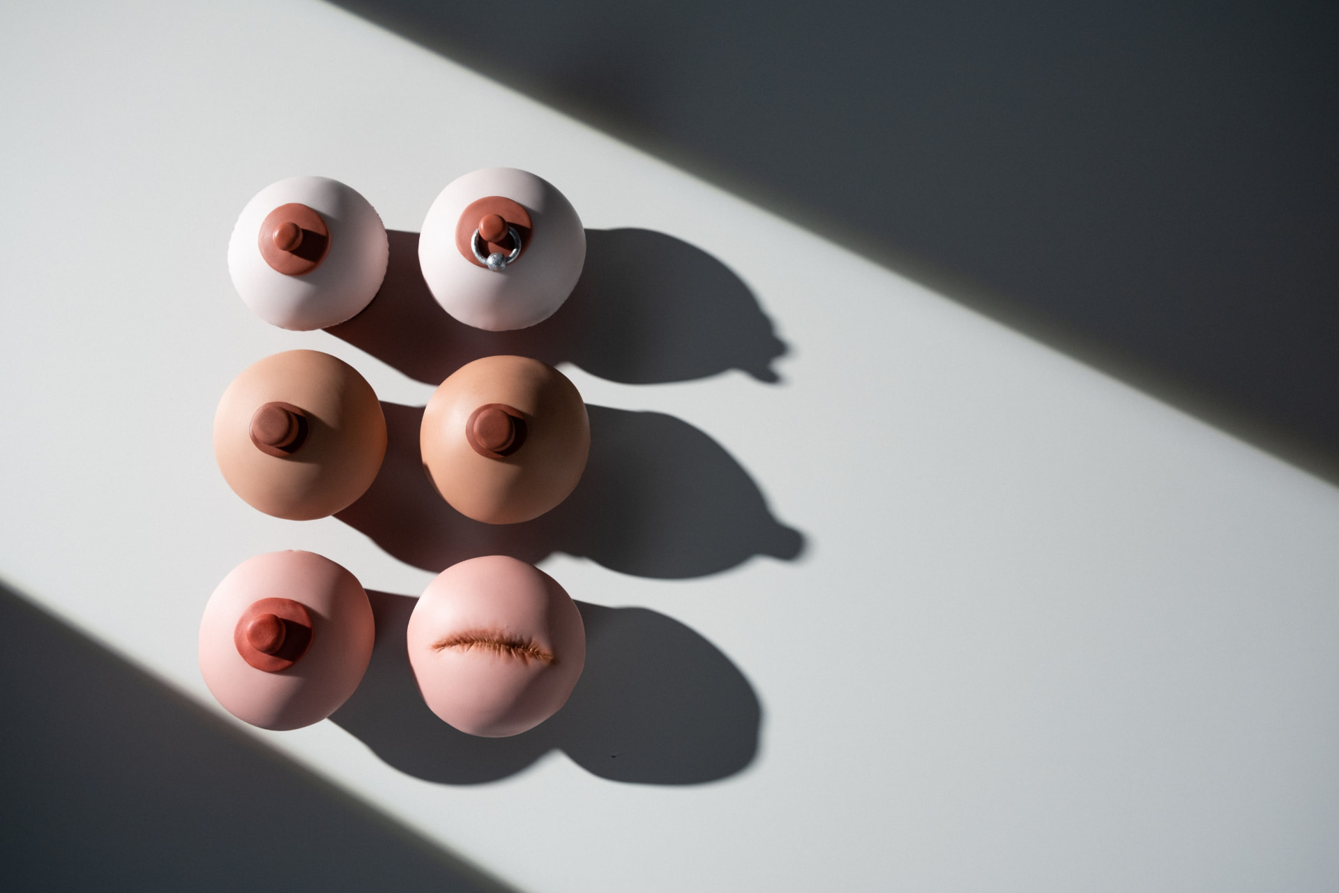 Silicone models representing diverse breast and nipple types, including a post-surgical scar